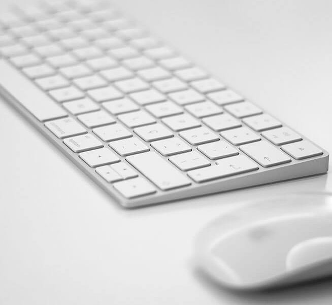 a computer keyboard and a mouse on a table.