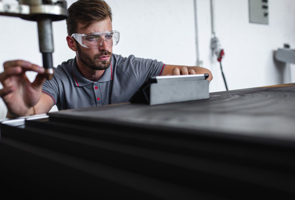 a man wearing safety goggles working on a laptop.