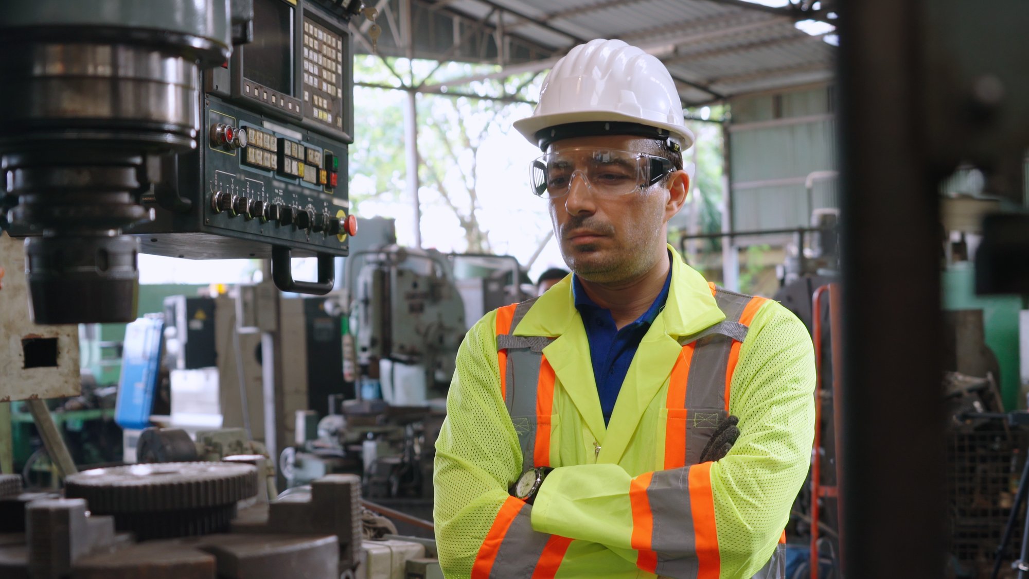 a man in safety gear standing in front of a machine.