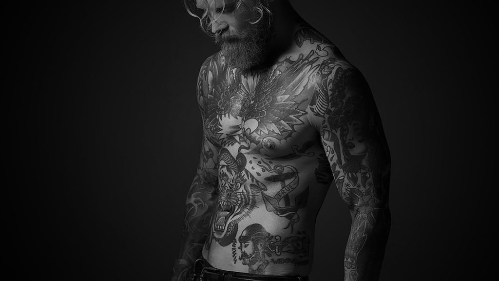 A man with tattoos on his body considering laser tattoo removal.