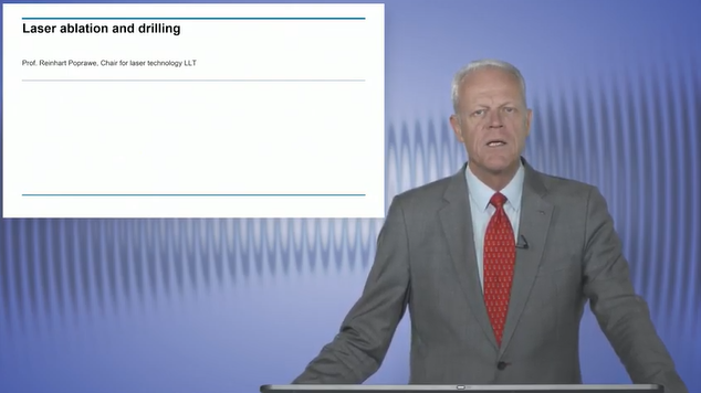 A man in a suit and tie standing in front of a screen demonstrating laser ablation.