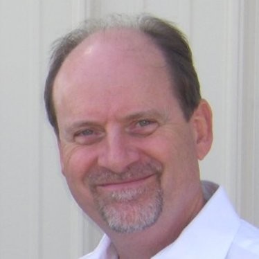 a man in a white shirt and tie smiling.