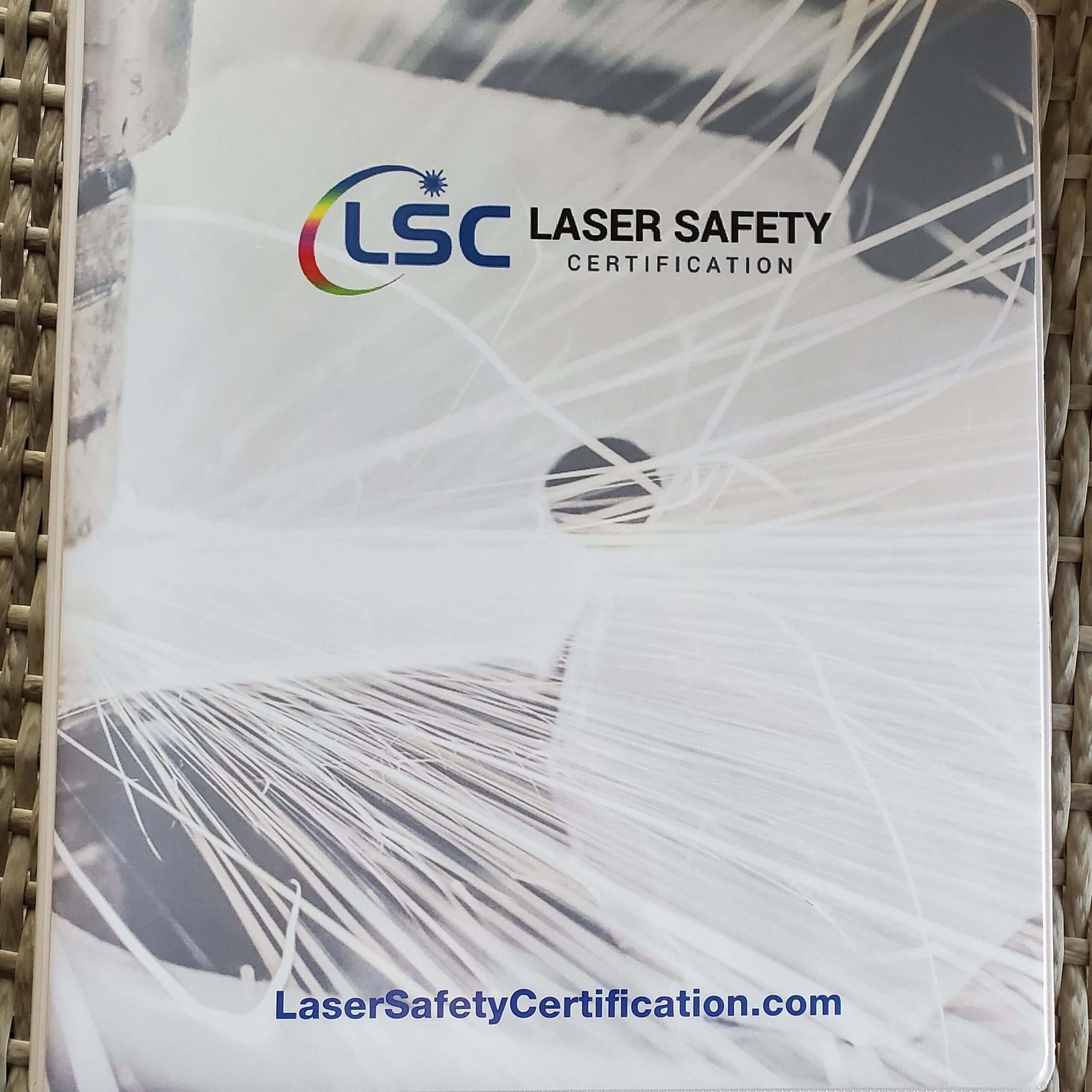 Laser safety officer certification manual on a wicker background.