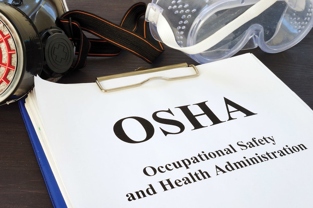 Manual on occupational safety and health administration (osha) with safety equipment including goggles and a respirator.